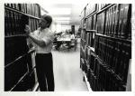 Male student searches for books in the library stacks
